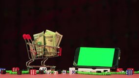 For Christmas, money in a basket and a phone with a green screen to insert. There are scattered dice and beads. A New Year's beam of light moves from behind against a dark background. 4K.