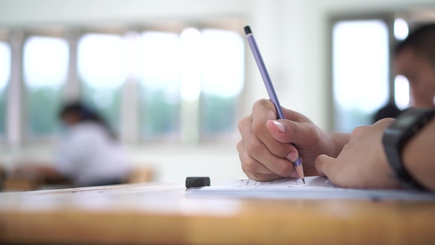 Hand Student use pencil writing on paper optical form of standardized test examination, Answer sheet, doing final exam attending in examination classroom. 4k Royalty-Free Stock Footage #1063389826
