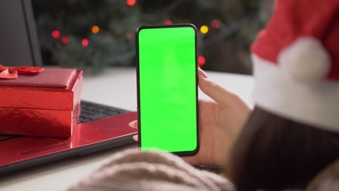 Close up shot of female in santa claus clothes , holding a smartphone with chroma key mock up green screen - technology, connections, communications concept 4k video template