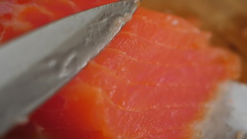 Healthy Eating Sea Food Omega. Man Cutting Red Fish Salmon On Wooden Board Close Up. Chef Cuts Redfish, Most Delicious Meat Slow Motion. Macro Chef Cuts Salmon Fillet Slices For Cooking Sushi Closeup.