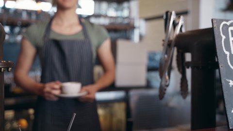 Female barista hold coffee cup serving a client at the coffee shop