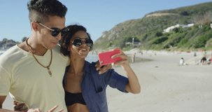 beautiful Mixed race couple taking selfies on the beach pulling funny faces on summer vacation 