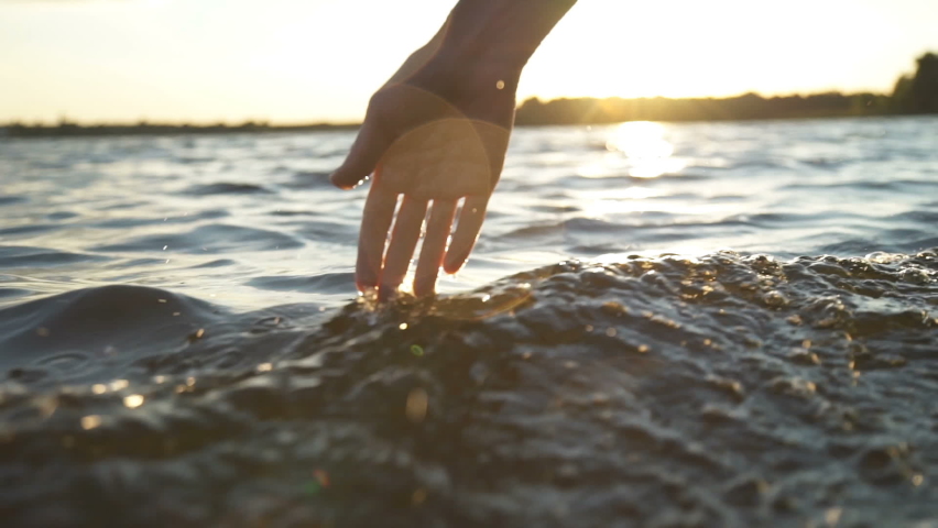 Close up woman hand gently touches the surface of the water in the sea | Shutterstock HD Video #1063412932