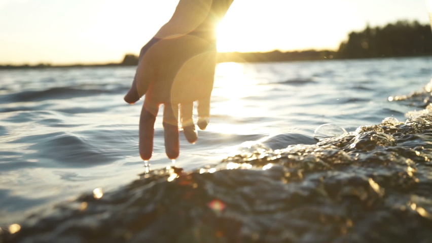 Close up woman hand gently touches the surface of the water in the sea | Shutterstock HD Video #1063412932