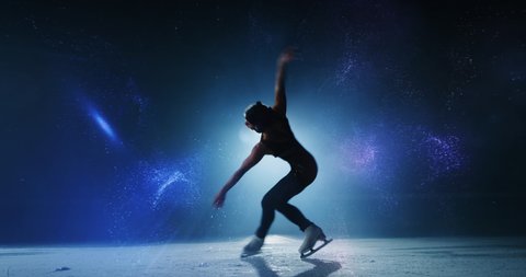 Cinematic shot of young female figure skater with headphones is performing choreography on ice rink with glowing polygonal graphics. Concept of technology, art and music.
