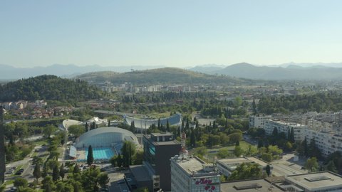 Drone flying over the streets of the old town where downtown, houses, skyscrapers, cars, trees, mountains on the background and urban landscape. Aerial shot Podgorica Montenegro.