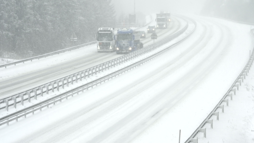 Wide locked down shot of two snow ploughs driving up the highway and clearing the snow off the road in snowfall. Royalty-Free Stock Footage #1063415944
