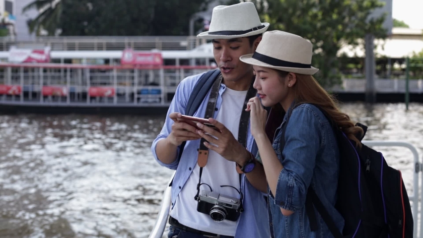 Traveler Asian couple travel in riverside Bangkok, Thailand, sweet couple taking photo  spending holiday trip in sunset. Young fun happy Asian tourist backpacker travel. Royalty-Free Stock Footage #1063416055