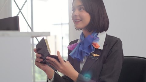 young asian smiling  woman  security agent at an airport working at the check-in desk for boarding a flight handing back a passport and ticket.