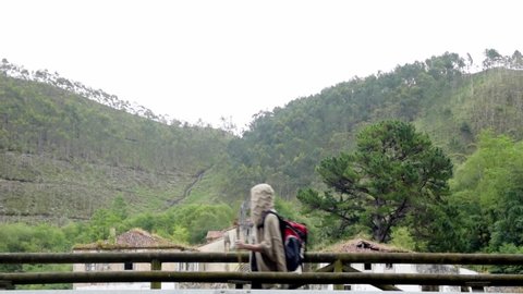 Side view of unrecognizable hiker with backpack and trekking stick walking near ancient monastery of San Antolin de Bedon during pilgrimage on Camino de Santiago in Spain