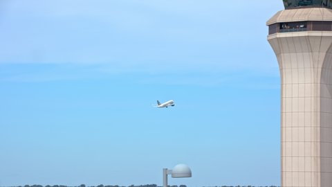 Generic Airport Air Traffic Control Tower with Departing Commercial Passenger Jet Airliner Taking Off past the ATC Communications Tower Flying into a Blue Sky on a Sunny Day