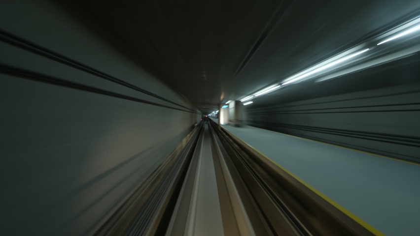 Front cabin view of automated people mover run fast at underground way, between airport terminals. Train make quick stop and race to second station. Blurred view of short tunnels Royalty-Free Stock Footage #1063423558