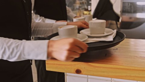 4k medium steadicam video of waiter and coffee on a tray, walking to a customer in hotel or restaurant cafe. 