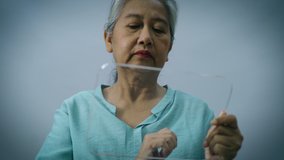 High tech concept of an Asian active senior woman using a futuristic transparent touchscreen pad