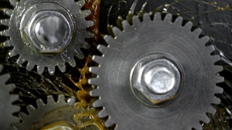 Super Slow Motion Detail Shot of Gear Mechanism and Oil on Dark Background at 1000 fps.