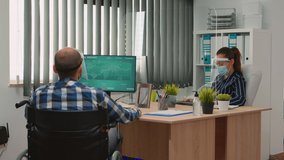Workers talking wearing protection face masks in new normal office during coronavirus, businessman moving with wheelchair. Immobilized man and coworker in corporate company respecting social distance. - Powered by Shutterstock - Get 15% off with code: PIKWIZARD15
