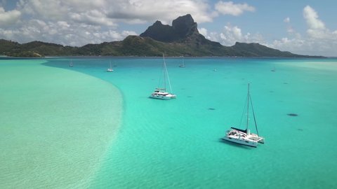 Drone Tahiti, 4k. Aerial view Bora Bora, Sailboat catamaran in blue lagoon. French Polynesia. Tropical paradise island. Exotic travel vacation getaway, romantic honeymoon destination.