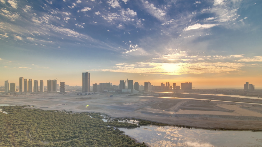 Skyscrapers on Al Reem and Al Maryah Island in Abu Dhabi at sunset timelapse from above. Aerial citiscape from Al Reem Island with modern buildings. Orange sky