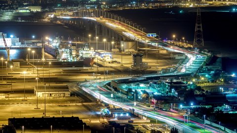 New Sheikh Khalifa Bridge in Abu Dhabi night timelapse aerial view from above, United Arab Emirates. Traffic on the road and ship in port