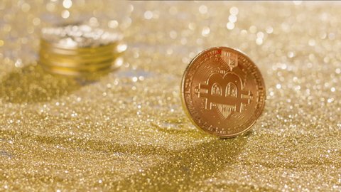 Bitcoin gold coin spins on the golden sand, then falls. Bitcoin mining concept. Blackmagic Ursa Pro G2, 300fps.