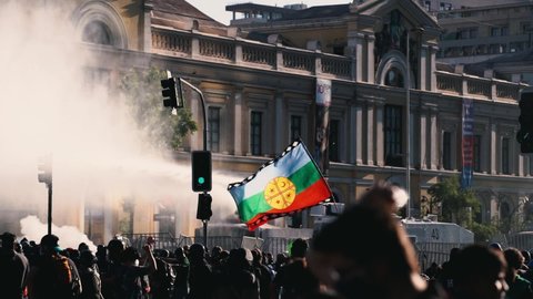 SANTIAGO, CHILE - November 28, 2020 Car launches water shoots at protesters while the flags of the Mapuche people are hit by the water in the middle of demonstrations in the center of the City by the 