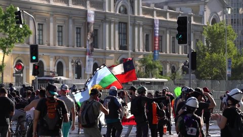 SANTIAGO, CHILE - November 28, 2020 A protester raises the Chilean flag and another protester raises the flag of the Mapuche people in the center of the city amidst protests for the government of Seba