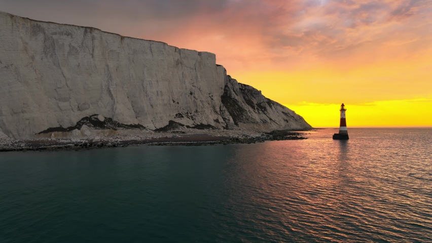 Landscape aerial drone footage video of a Beachy Head Lighthouse and chalk cliffs at colourful sunrise  with low tide in England, near Eastbourne Royalty-Free Stock Footage #1063441660