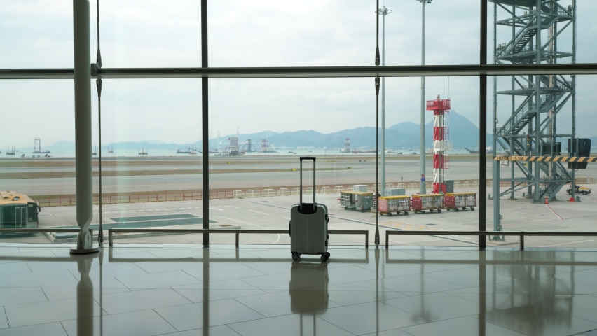 Forgotten trolley case stand against window, empty passage at airport concourse. Unattended bag left by scatterbrain passenger. Empty taxiway seen through glass wall on background Royalty-Free Stock Footage #1063441804