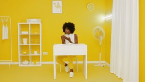 Stylish Afro-American woman is sitting at white desk in creative yellow room space, enjoying her snack time, eating tasty pizza with cheese, creative video, Slow motion.