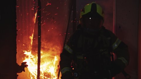 Firefighter helping to extinguish fire in burning house. High quality 4k footage