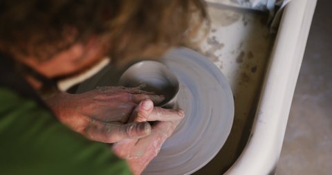 Close up view of male potter creating pottery on on potters wheel at pottery studio. hygiene and social distancing in the pottery studio during coronavirus covid 19 pandemic.