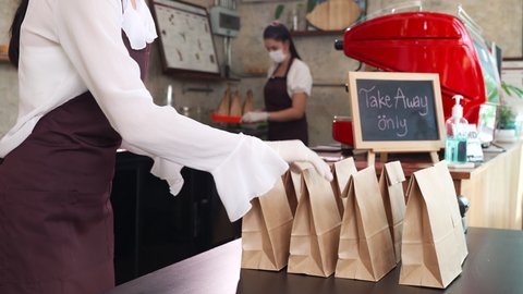 4K UHD Slow motion dolly shot : Asian Waitress Preparing order for take away curb side and delivery customer. This is essential popular service after city lockdown from coronavirus pandemic.