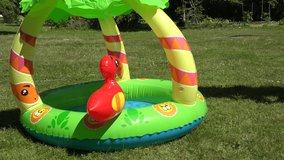 Mother habituate small child to rubber inflatable water pool outdoor in park. 4K UHD video clip.