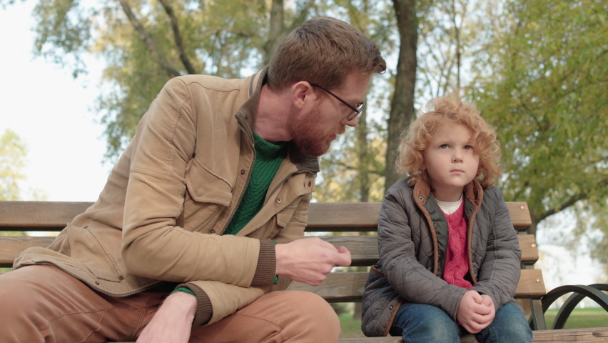 Red-haired father talking to son, helping to solve problem, family connection