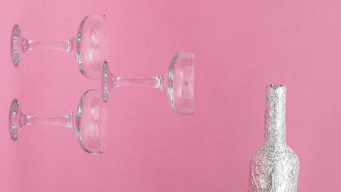 Stop motion video of Pouring champagne from bottle to glasses on pink background. Celebration Cristmas concept. Vertical video.