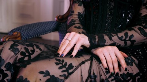 Confident woman in gothic dress fingering hands close up. Rich jewelry sexy goth girl. Female fingering arm. Gothic dressing with stylish diamonds. Person gestures hand waiting. Black nail on finger.