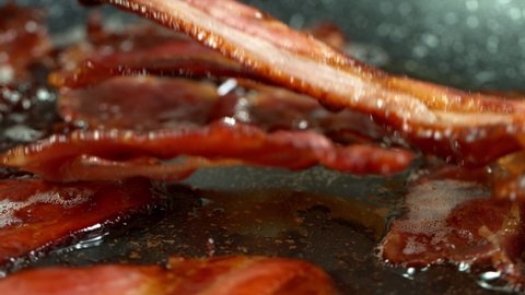 Super Slow Motion Shot of Roasted Bacon Slices Falling into Pan at 1000 fps.