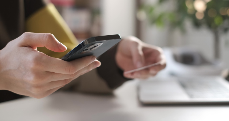 Female hand holding credit card and shopping online. Easy pay using digital gadget. Girl using laptop at home. Happy woman with smartphone and bank card shopping online. Buying gifts. Lifestyle 4K