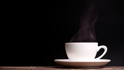 Coffee cup with natural steam smoke of coffee on dark background with copy space, slow motion. Hot Coffee Drink Concept.