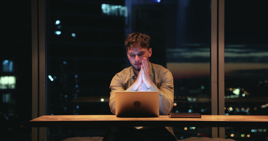 Serious millennial employee sit at desk develop start up ideas, search problem solution working hard use laptop app at night in modern skyscrapers office room. Deadline, careerism, workaholism concept | Shutterstock HD Video #1063468477
