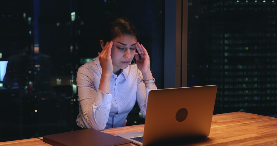 Tired overworked workaholic indian female employee sit at workplace desk in modern office using laptop working on deadline task, urgent project feels exhausted. Over hours job, hard-working concept | Shutterstock HD Video #1063468537