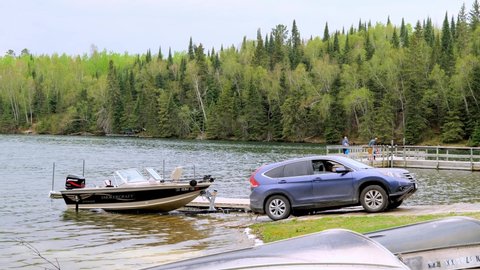 CLEARWATER CO, MN - 23 MAY 2020: Automobile pulling fishing boat and trailer out of the water at a Minnesota lake. Handheld clip about boating.