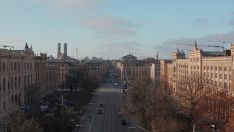 Main Road through Cityscape center of German City Munich with classic buildings and tram rails and car traffic, Scenic Aerial Dolly in