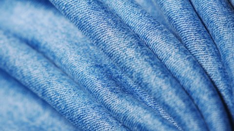 Wavy denim surface. Microtexture. The classic fabric for making jeans. Seams and threads close up. Smooth rotation