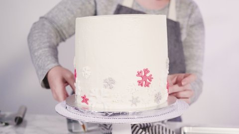 Step by step. Decorating round funfetti cake with pink and white fondant snowflakes.