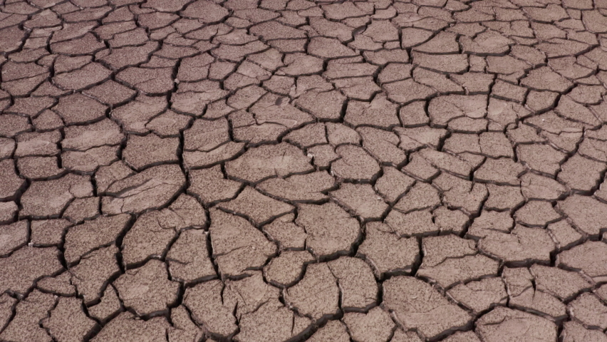 A view of a cracked surface of a parched lake. The concept of global warming, environmental pollution and post-apocalypse | Shutterstock HD Video #1063484713