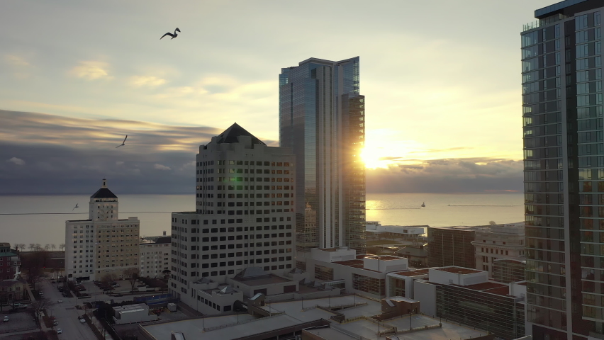 Sunrise over the Lake Michigan in Milwaukee, Wisconsin. Seagulls flying over modern buildings, skyscrapers. Cloudy sky, sun shining