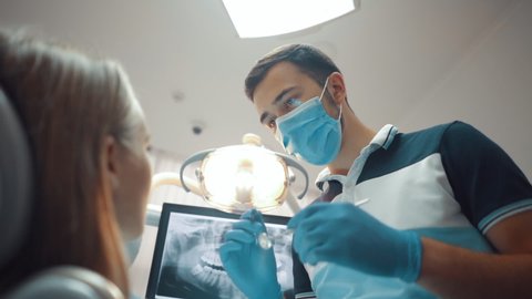 A male dentist examines a patient in a dental office. Dental treatment and care. Oral hygiene. Health care and medicine concept.