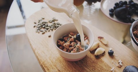 Woman Preparing Healthy Breakfast Bowl with Blueberries Fruits Nuts and Granola at Home Kitchen. Concept Of Diet, Proper Nutrition And Healthy Pregnancy and People