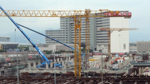 HONG KONG - APRIL 14, 2018: Lively construction works at Chek Lap Kok island against airport terminal, time lapse shot. Cranes turn and lift materials, workers figures move around site
